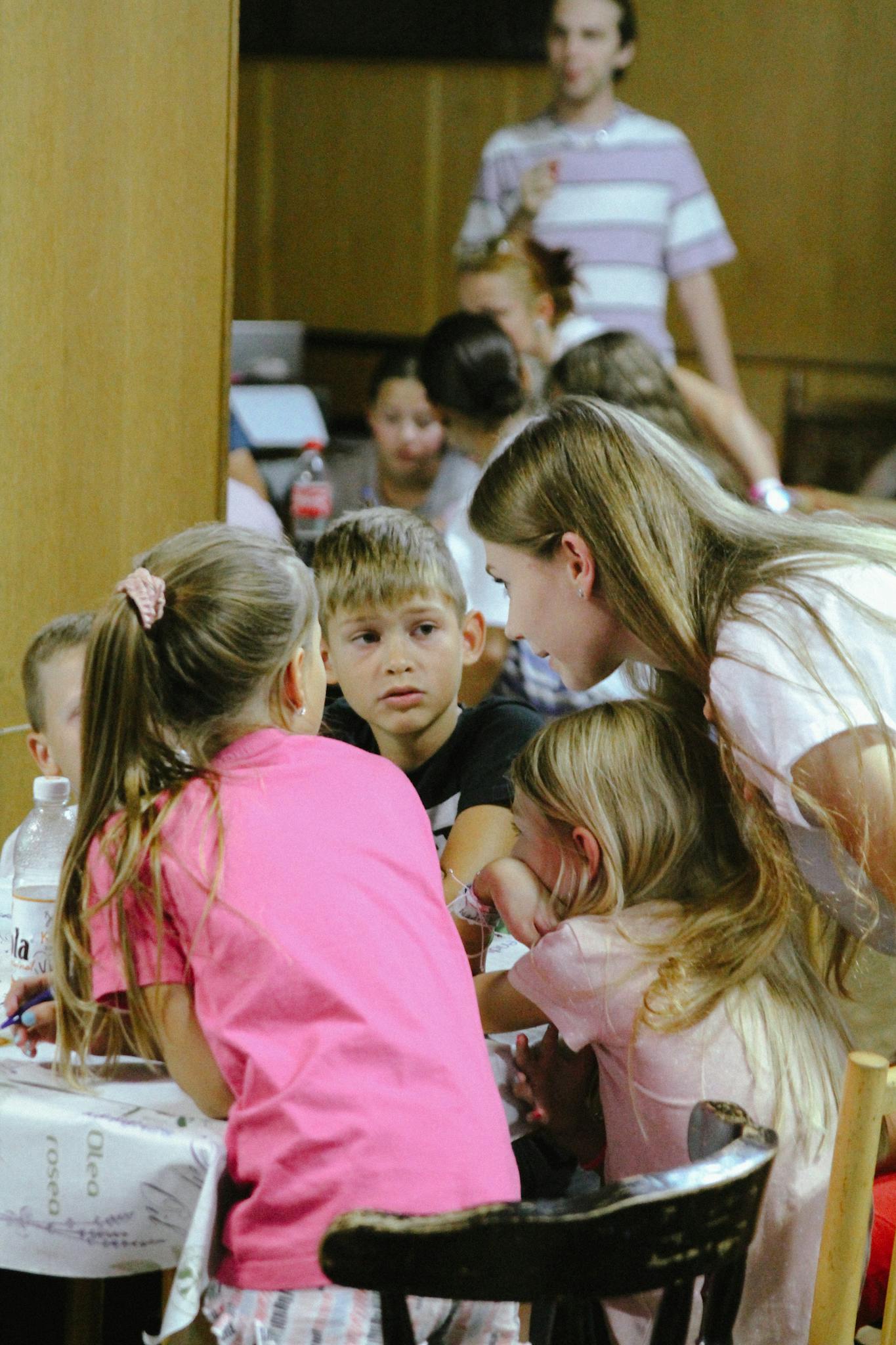 Group of children involved in a lively discussion at a table indoors.